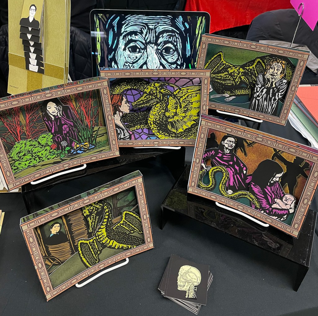 A series of colorful tunnel books depicting the story of a dragon sit on a table with a black tablecloth